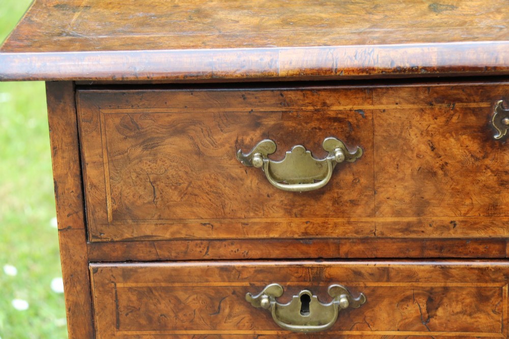A George II burr elm lowboy featuring three drawers, brass drop handles, a scalloped apron, and cabriole legs terminating in pad feet. View III
