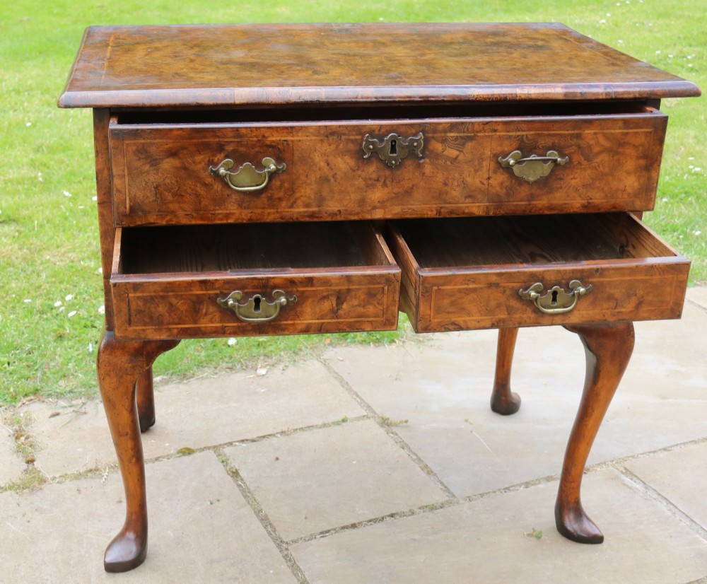 A George II burr elm lowboy featuring three drawers, brass drop handles, a scalloped apron, and cabriole legs terminating in pad feet. View VII