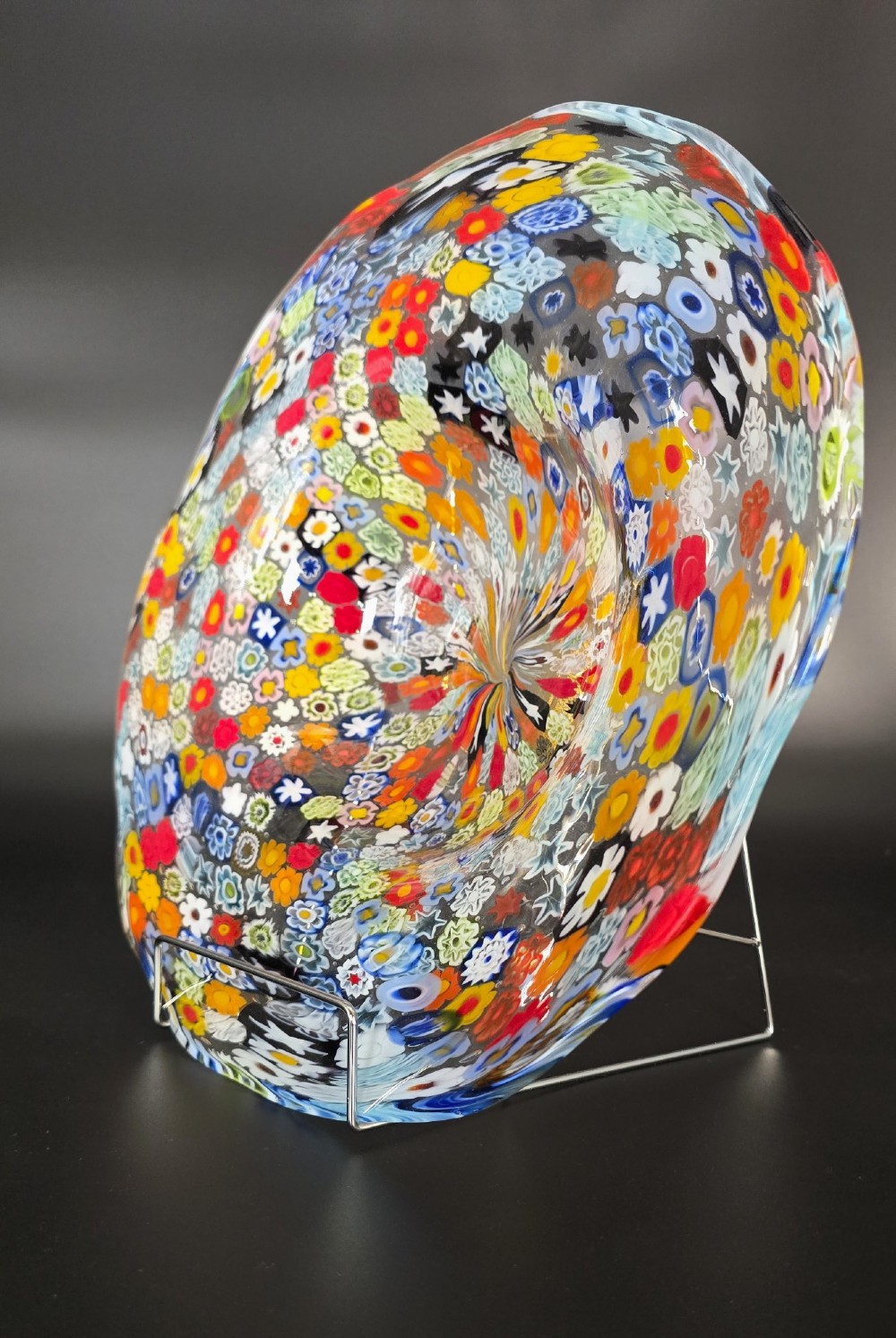 A circular Murano millefiori glass bowl featuring dense, colourful mosaic cane patterns arranged in starburst and floral formations. View III