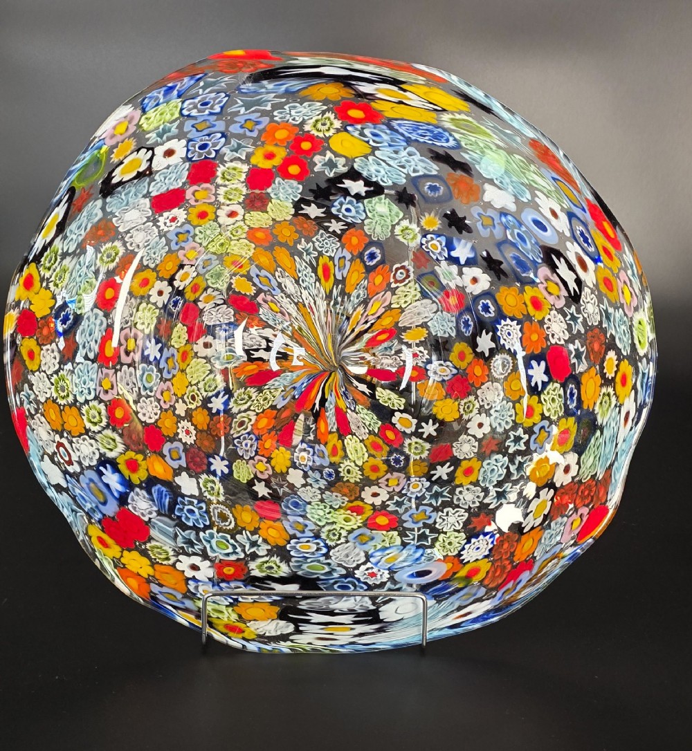 A circular Murano millefiori glass bowl featuring dense, colourful mosaic cane patterns arranged in starburst and floral formations. View IV