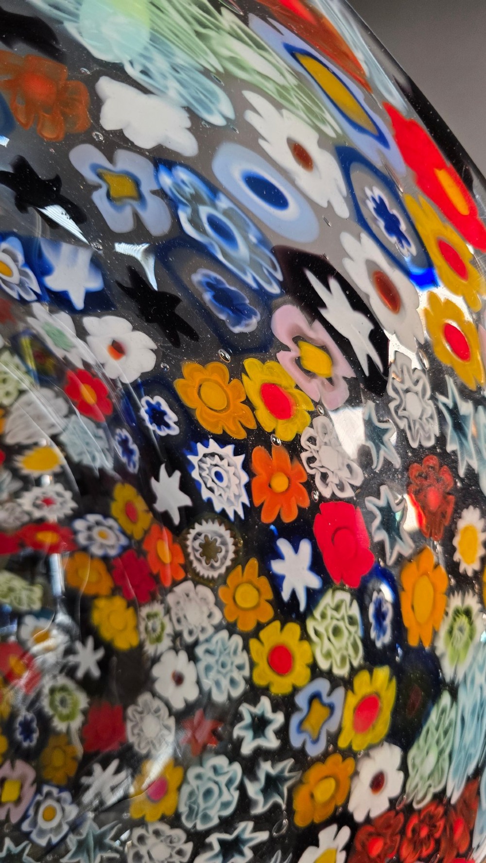 A circular Murano millefiori glass bowl featuring dense, colourful mosaic cane patterns arranged in starburst and floral formations. View VI