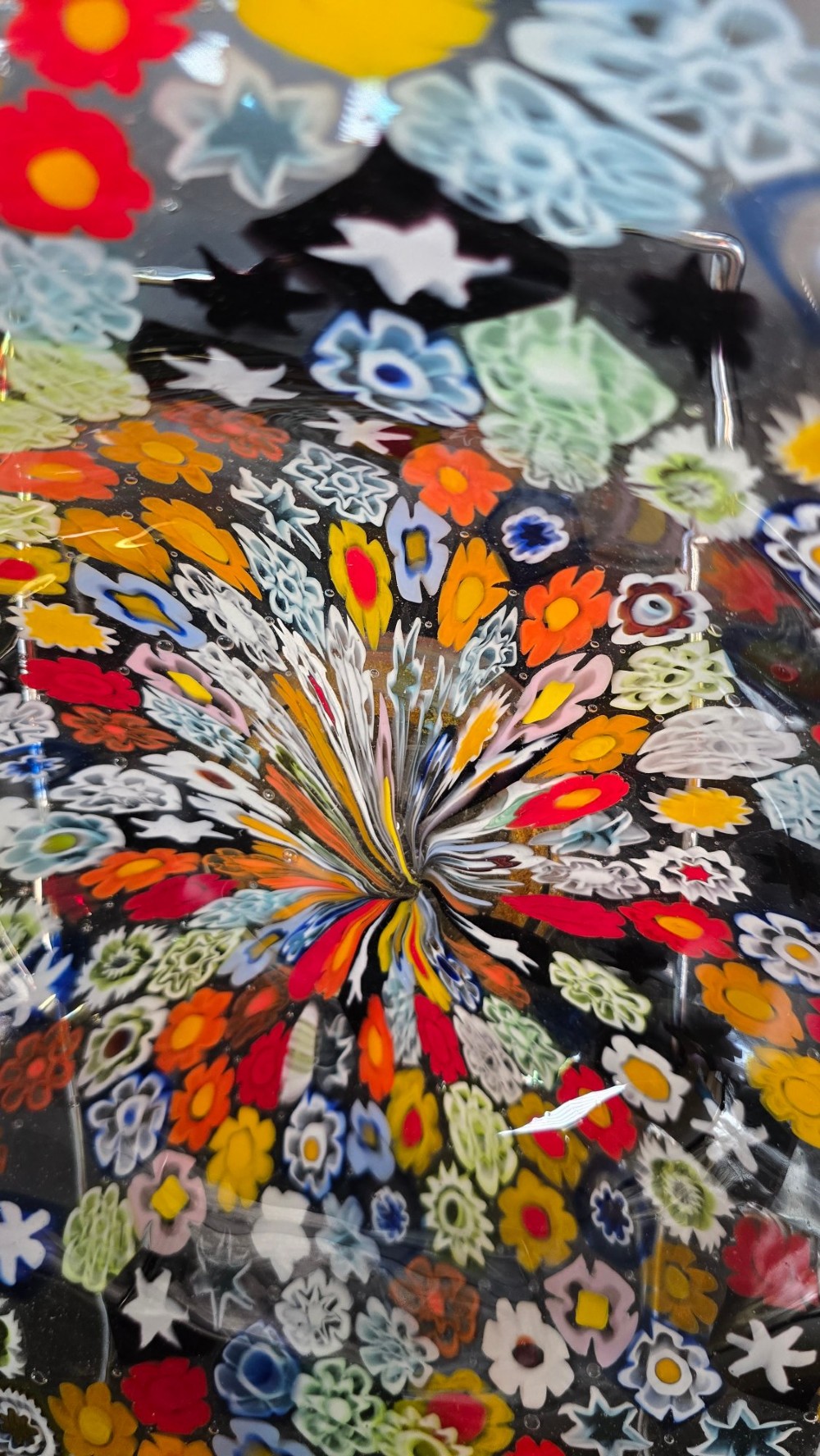 A circular Murano millefiori glass bowl featuring dense, colourful mosaic cane patterns arranged in starburst and floral formations. View VII