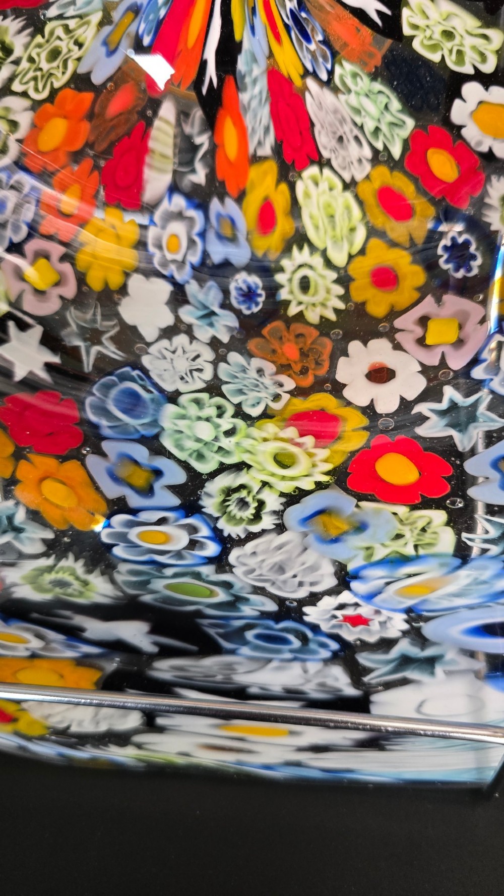 A circular Murano millefiori glass bowl featuring dense, colourful mosaic cane patterns arranged in starburst and floral formations. View IX