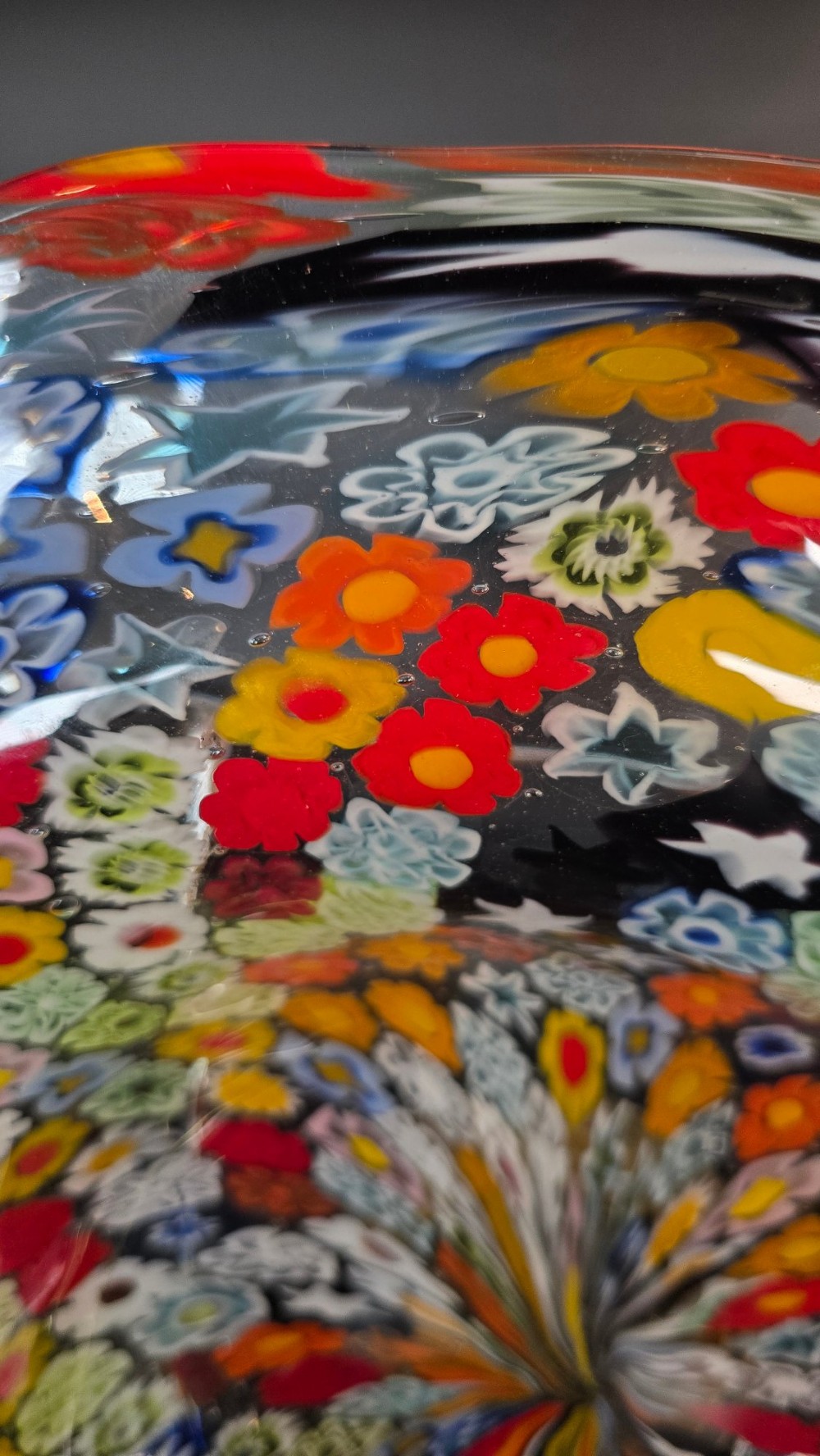 A circular Murano millefiori glass bowl featuring dense, colourful mosaic cane patterns arranged in starburst and floral formations. View X