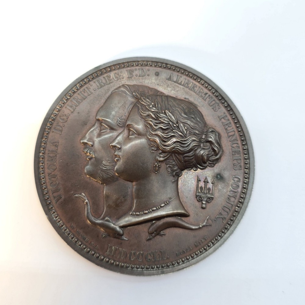 A circular dark bronze Victorian medal displaying jugate profile portraits of Queen Victoria and Prince Albert surrounded by Latin text.