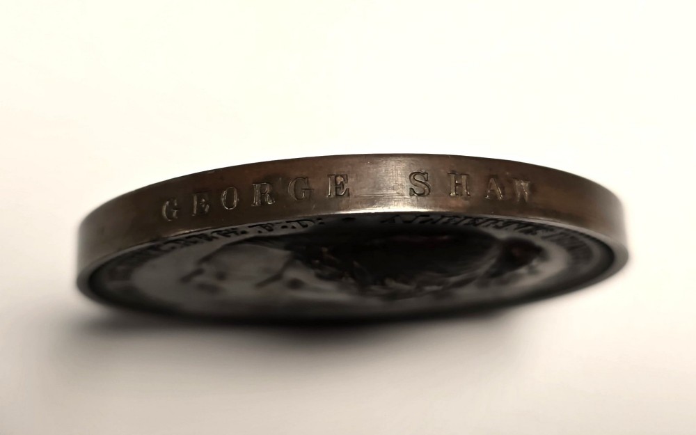 A circular dark bronze Victorian medal displaying jugate profile portraits of Queen Victoria and Prince Albert surrounded by Latin text. View IV