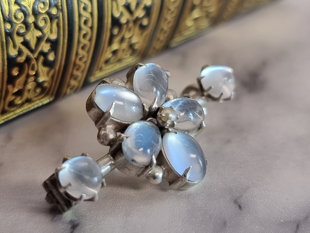 An antique silver bar brooch featuring a central flower cluster of oval cabochon moonstones flanked by single moonstones on either side. View III