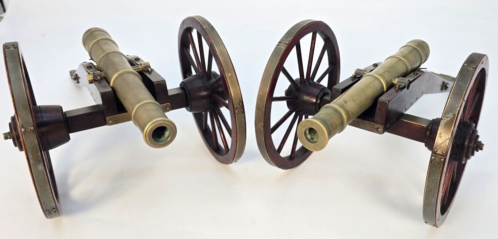 A pair of 1920s model field cannons featuring cast brass barrels mounted on dark wooden spoked-wheel carriages. View III