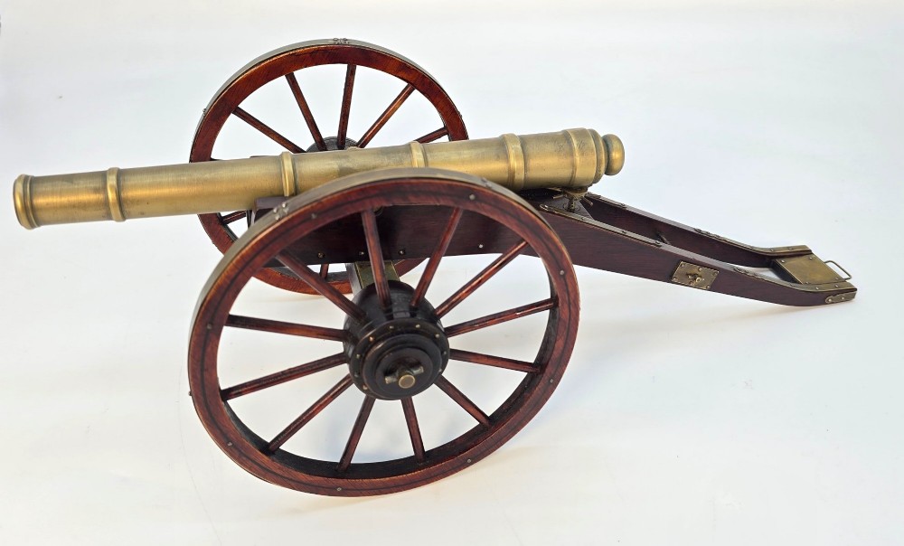 A pair of 1920s model field cannons featuring cast brass barrels mounted on dark wooden spoked-wheel carriages. View V