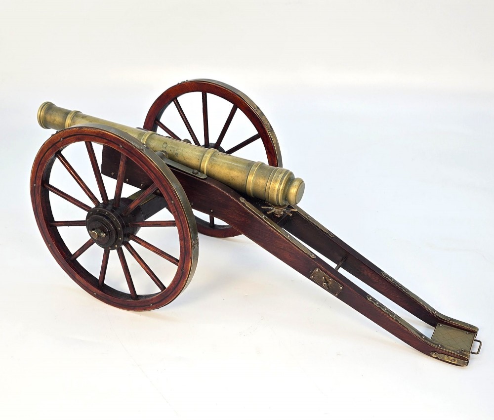 A pair of 1920s model field cannons featuring cast brass barrels mounted on dark wooden spoked-wheel carriages. View VI