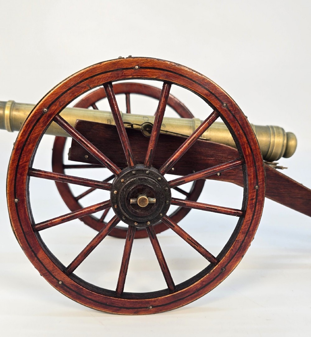 A pair of 1920s model field cannons featuring cast brass barrels mounted on dark wooden spoked-wheel carriages. View VII