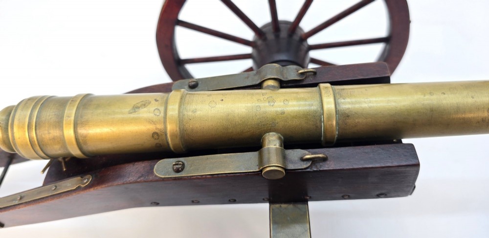 A pair of 1920s model field cannons featuring cast brass barrels mounted on dark wooden spoked-wheel carriages. View XII