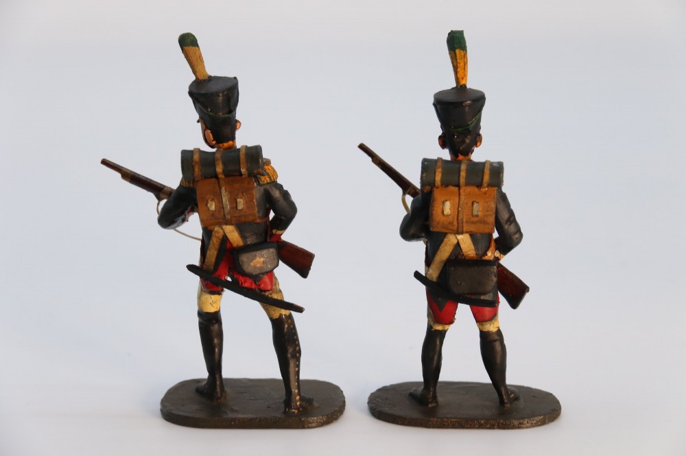 A group of ten hand-carved and painted wooden figures depicting Napoleonic infantry soldiers with muskets standing on individual oval bases. View IV