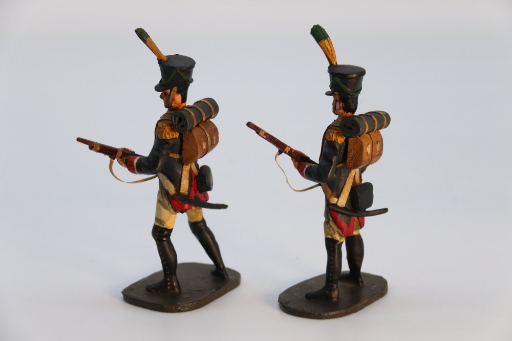 A group of ten hand-carved and painted wooden figures depicting Napoleonic infantry soldiers with muskets standing on individual oval bases. View V