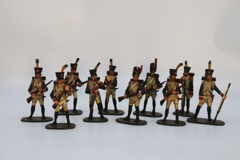 A group of ten hand-carved and painted wooden figures depicting Napoleonic infantry soldiers with muskets standing on individual oval bases. View IX