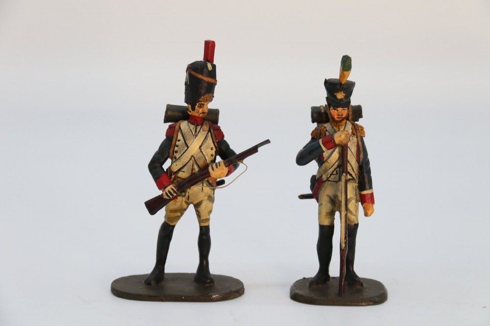 A group of ten hand-carved and painted wooden figures depicting Napoleonic infantry soldiers with muskets standing on individual oval bases. View XII