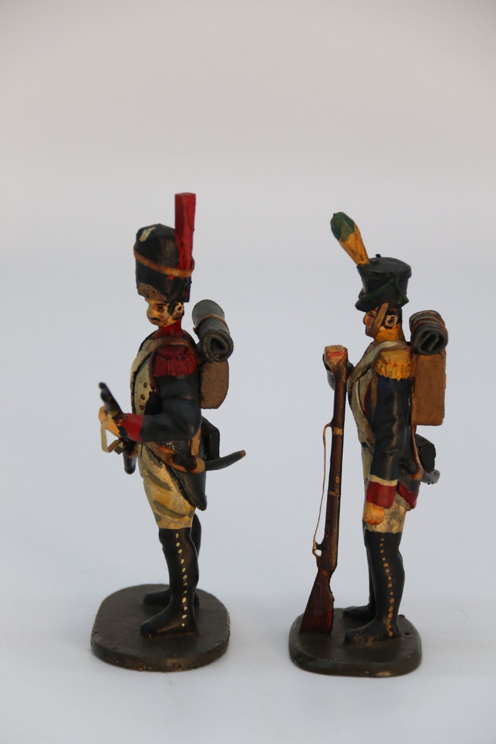 A group of ten hand-carved and painted wooden figures depicting Napoleonic infantry soldiers with muskets standing on individual oval bases. View XIV