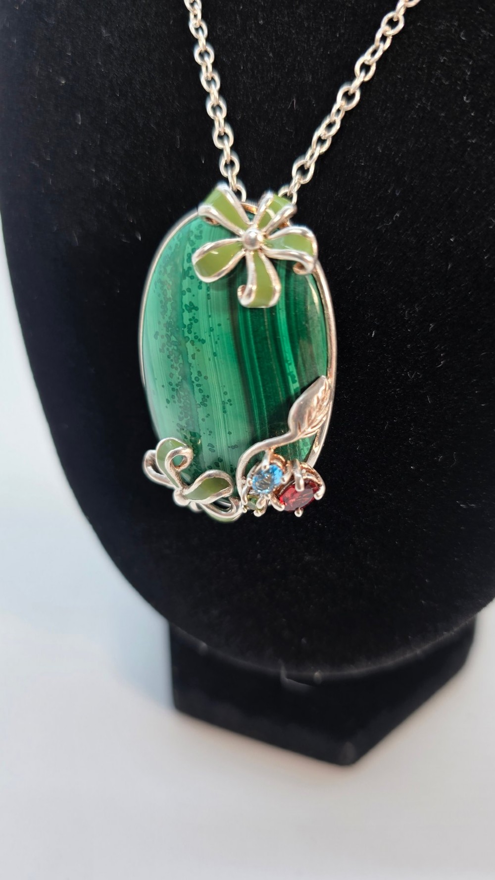 An oval green banded malachite pendant set in silver with floral enamel embellishments and small accent stones on a fine chain. View III