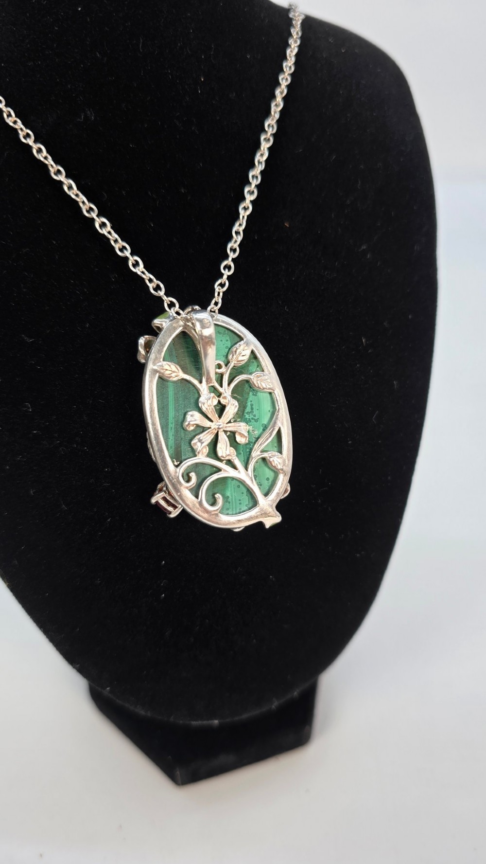 An oval green banded malachite pendant set in silver with floral enamel embellishments and small accent stones on a fine chain. View V