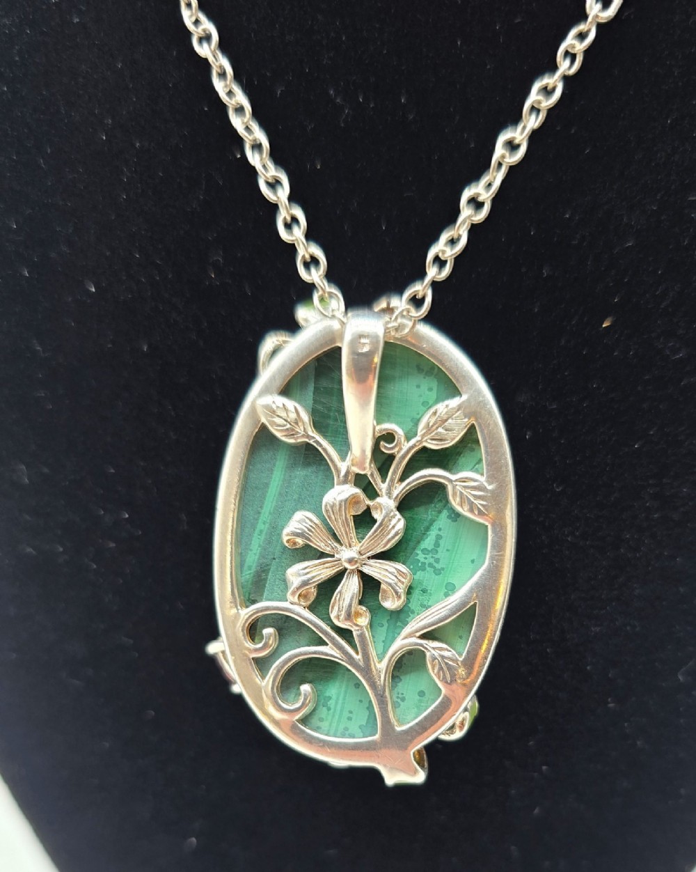 An oval green banded malachite pendant set in silver with floral enamel embellishments and small accent stones on a fine chain. View XII