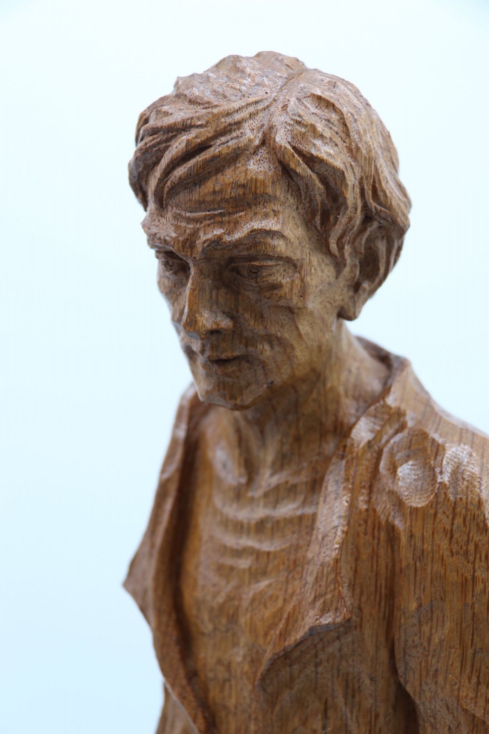 A hand-carved golden oak wooden sculpture of a male farm worker standing on a carved naturalistic base while holding a shallow tray. View IX