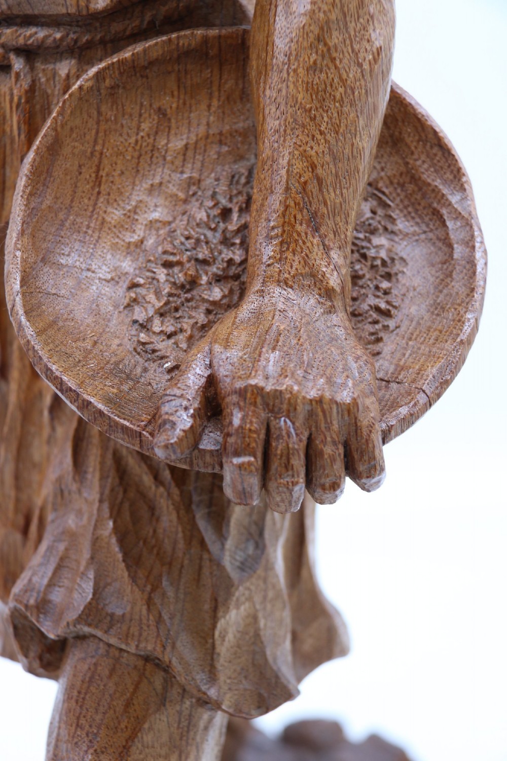 A hand-carved golden oak wooden sculpture of a male farm worker standing on a carved naturalistic base while holding a shallow tray. View X