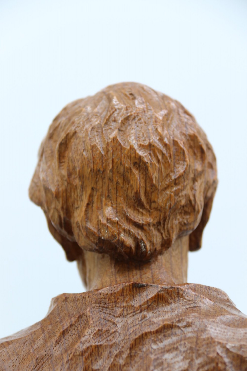 A hand-carved golden oak wooden sculpture of a male farm worker standing on a carved naturalistic base while holding a shallow tray. View XI