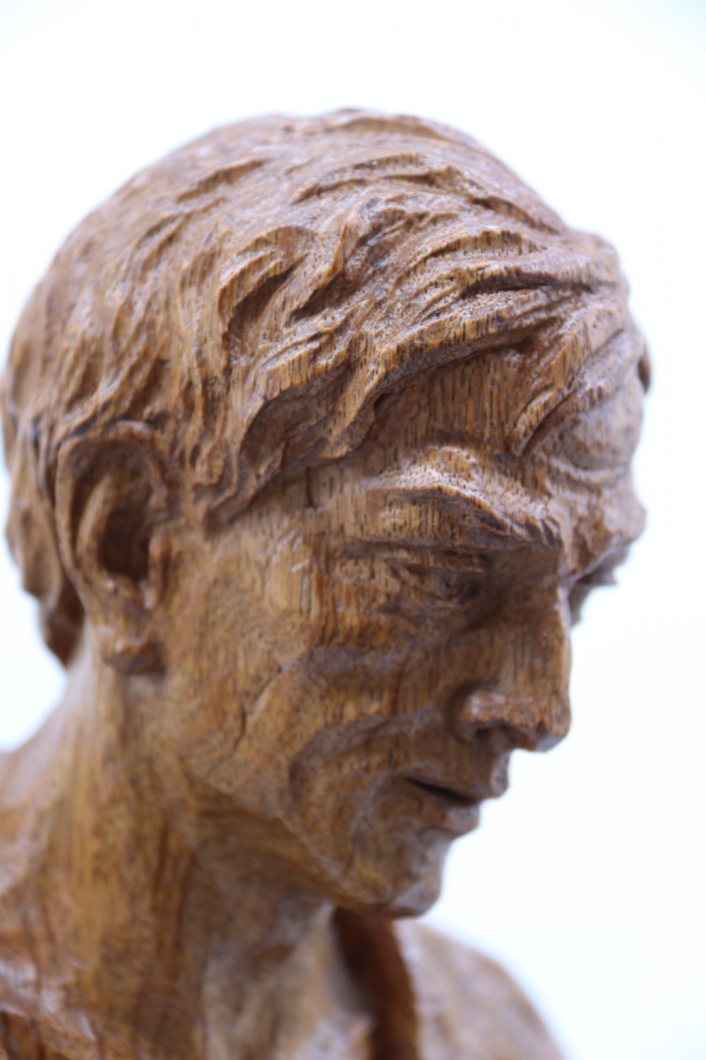 A hand-carved golden oak wooden sculpture of a male farm worker standing on a carved naturalistic base while holding a shallow tray. View XIII