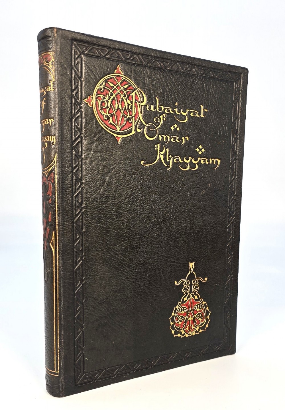 An Edwardian black leather bound edition of the Rubaiyat of Omar Khayyam featuring gilt and red embellished lettering with geometric corner tooling.