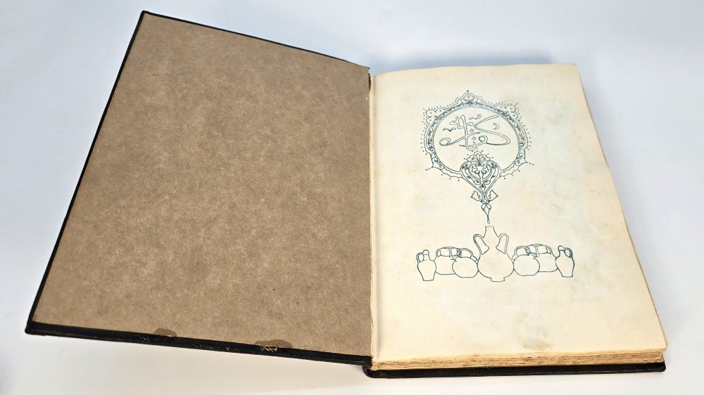 An Edwardian black leather bound edition of the Rubaiyat of Omar Khayyam featuring gilt and red embellished lettering with geometric corner tooling. View V