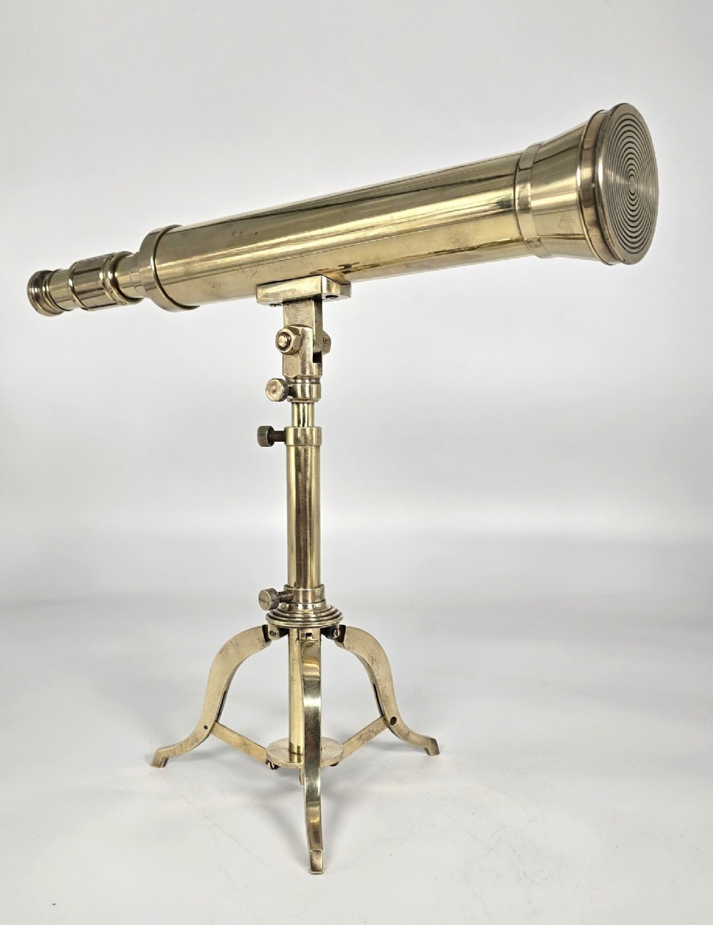 A Victorian brass table telescope mounted on a folding brass tripod stand.
