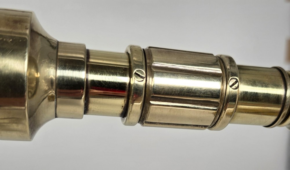 A Victorian brass table telescope mounted on a folding brass tripod stand. View XII