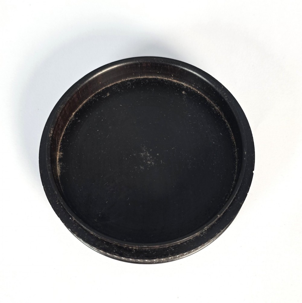A circular black ebony snuff box with intricate engine-turned geometric patterns and raised beaded details on the lid. View VIII
