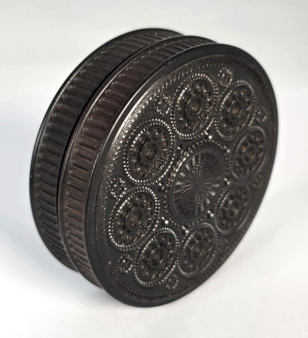 A circular black ebony snuff box with intricate engine-turned geometric patterns and raised beaded details on the lid. View XIII