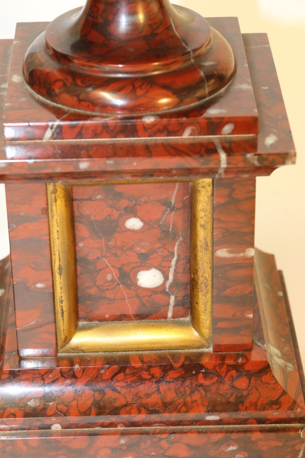 A late nineteenth-century French clock garniture in mottled red marble and gilt brass, featuring a central arch-topped mantel clock with a visible pendulum and two flanking urn cassolettes. View XI