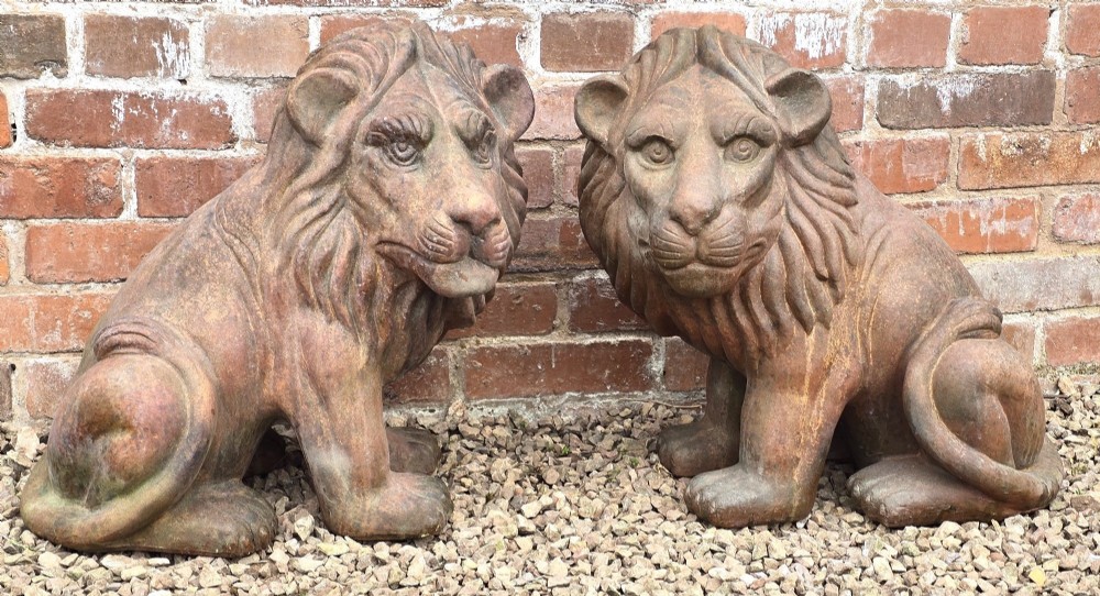 A pair of hand-sculpted Italian terracotta seated lions with weathered patination.