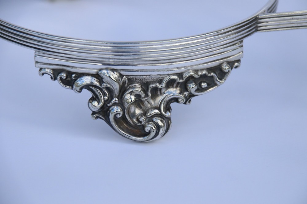 A silver-plated double frame holding two floral porcelain plates alongside a fitted cream jug and sugar bowl. View X