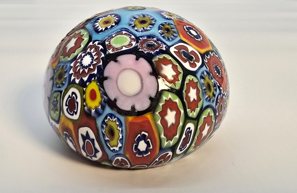 A spherical glass paperweight featuring a vibrant interior arrangement of colourful geometric and floral millefiori cane patterns. View VI