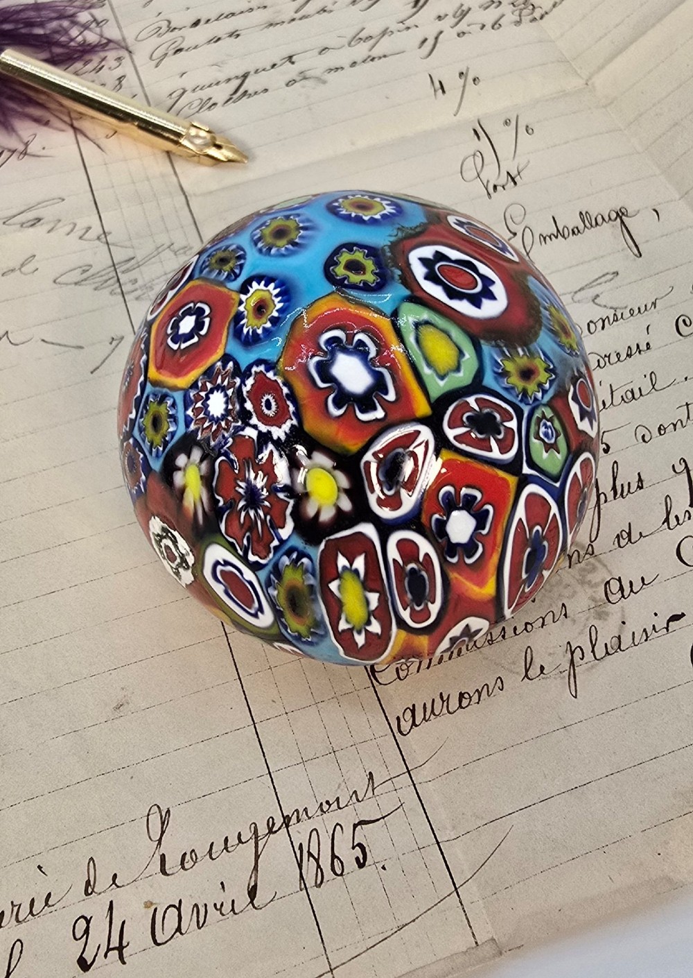 A spherical glass paperweight featuring a vibrant interior arrangement of colourful geometric and floral millefiori cane patterns. View VIII