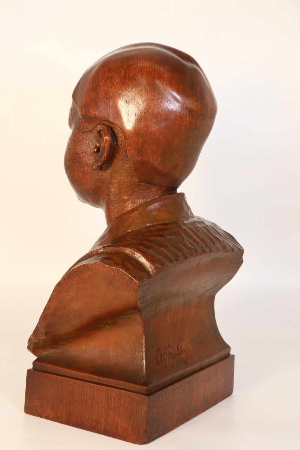 A carved walnut sculpture bust of a young child set upon a matching rectangular wooden plinth. View VI