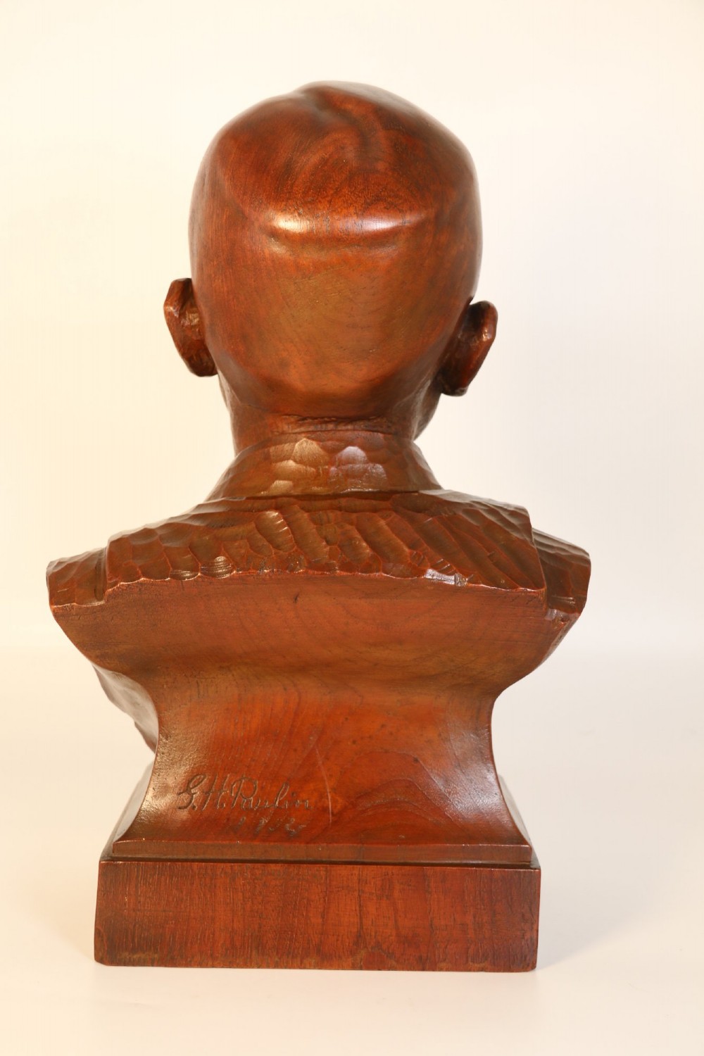 A carved walnut sculpture bust of a young child set upon a matching rectangular wooden plinth. View VII