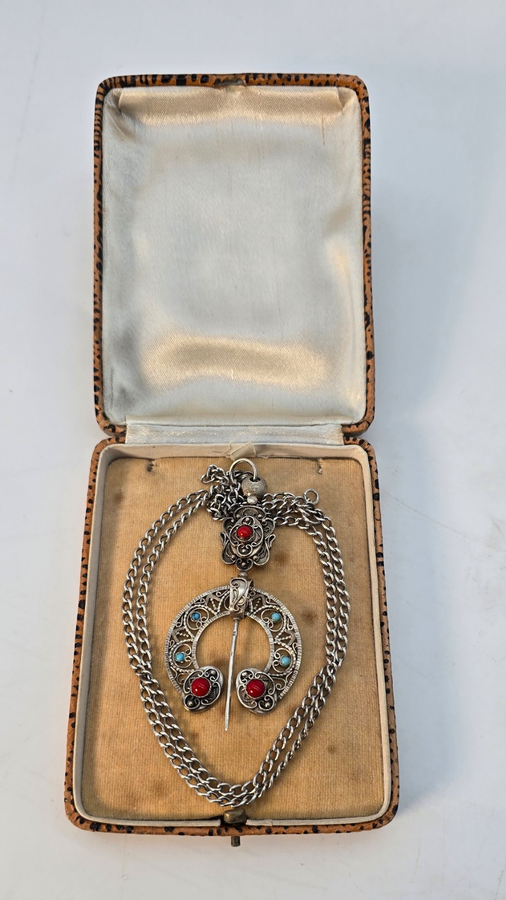 An antique late nineteenth-century French silver pendant in an Ottoman style featuring filigree work set with red and turquoise cabochons, suspended on a silver chain. View X