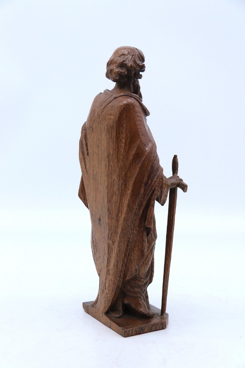 A carved oak wooden statue depicting Saint Paul holding a sword and scroll, standing on an octagonal wooden base. View IV