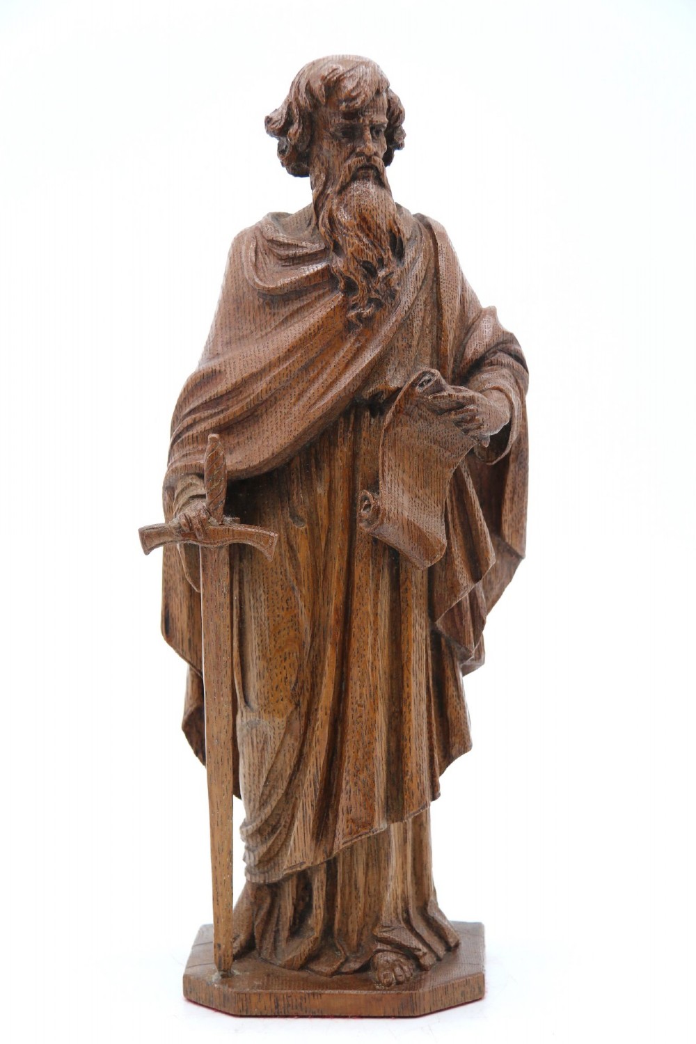 A carved oak wooden statue depicting Saint Paul holding a sword and scroll, standing on an octagonal wooden base. View VII