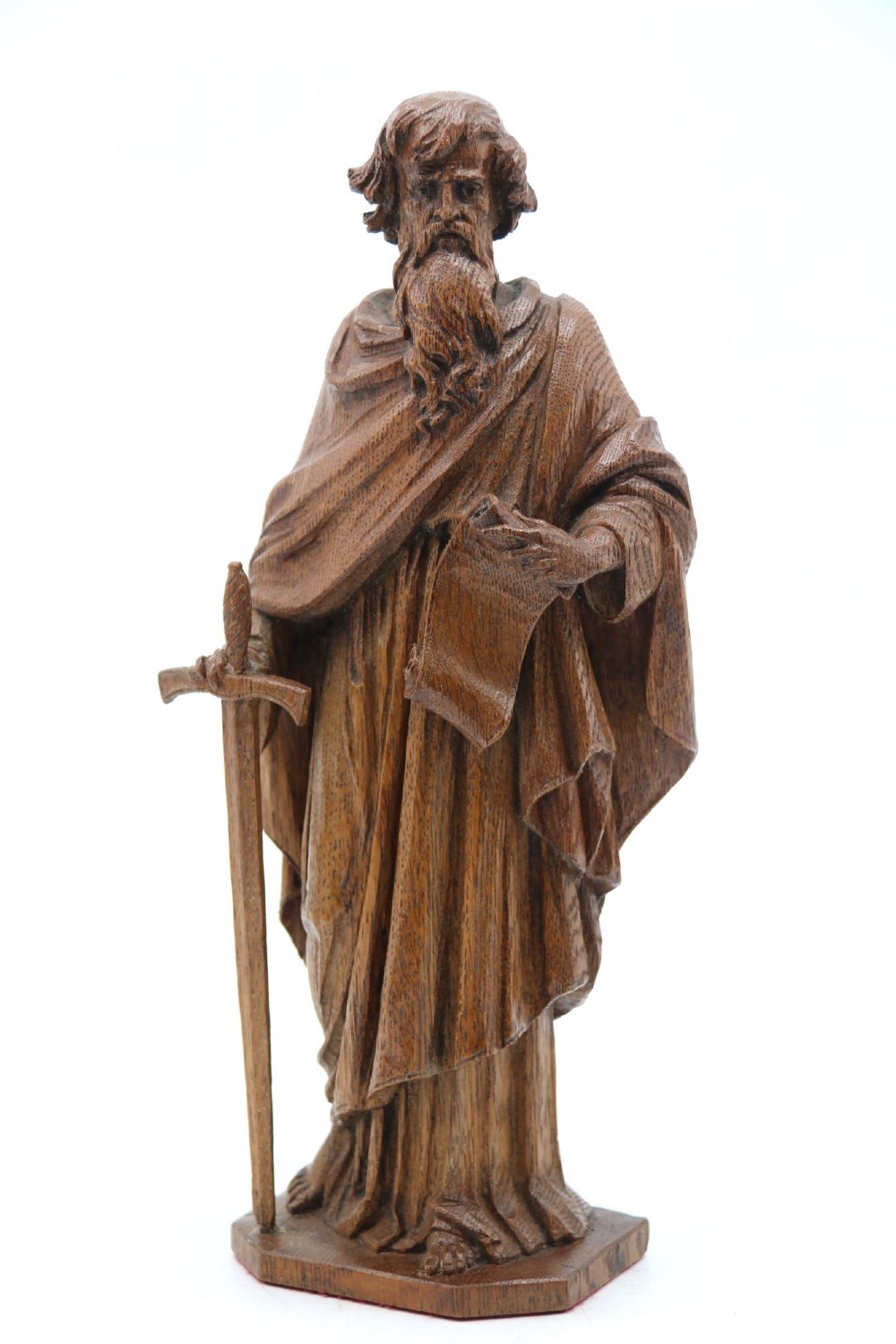 A carved oak wooden statue depicting Saint Paul holding a sword and scroll, standing on an octagonal wooden base. View VIII