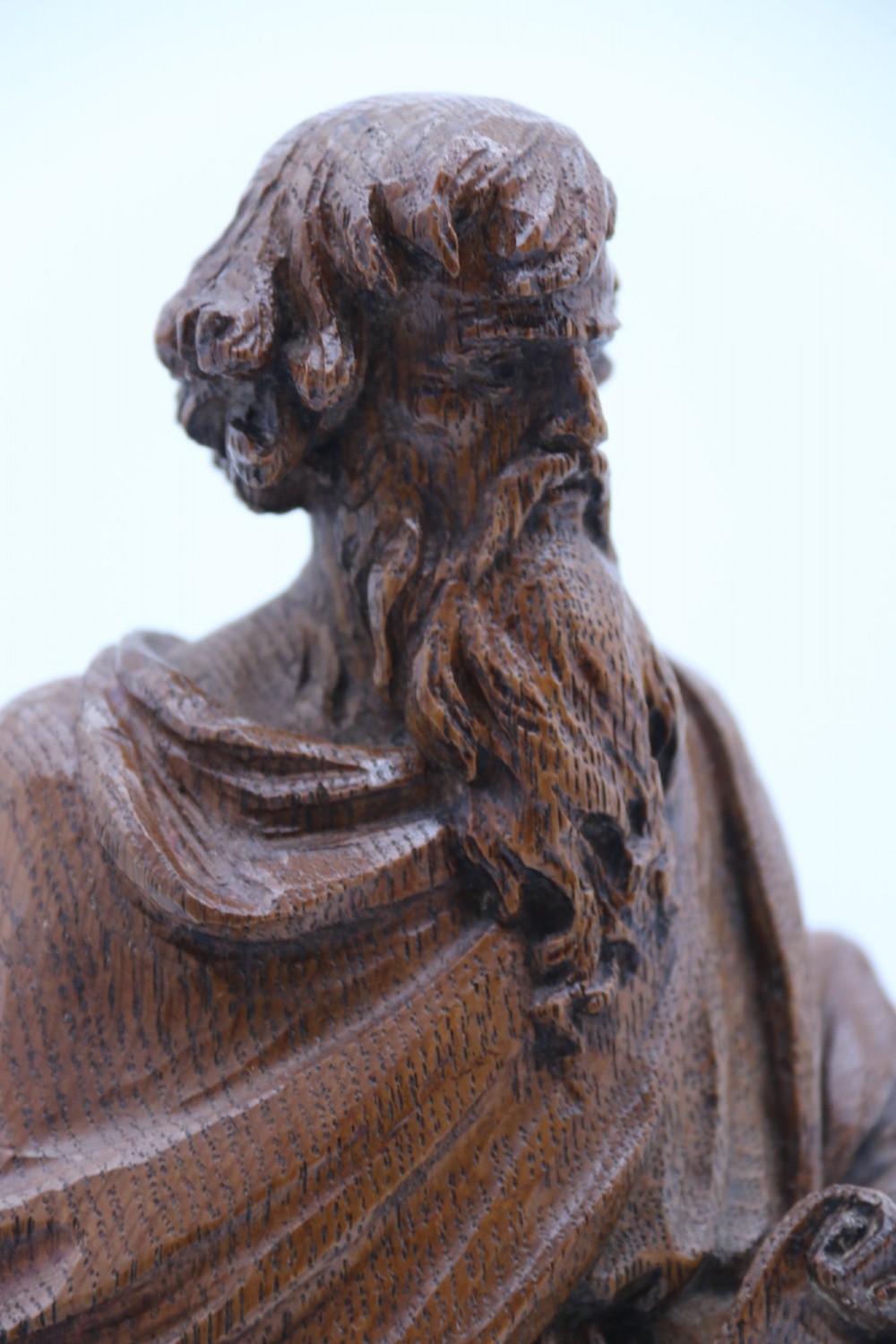 A carved oak wooden statue depicting Saint Paul holding a sword and scroll, standing on an octagonal wooden base. View X