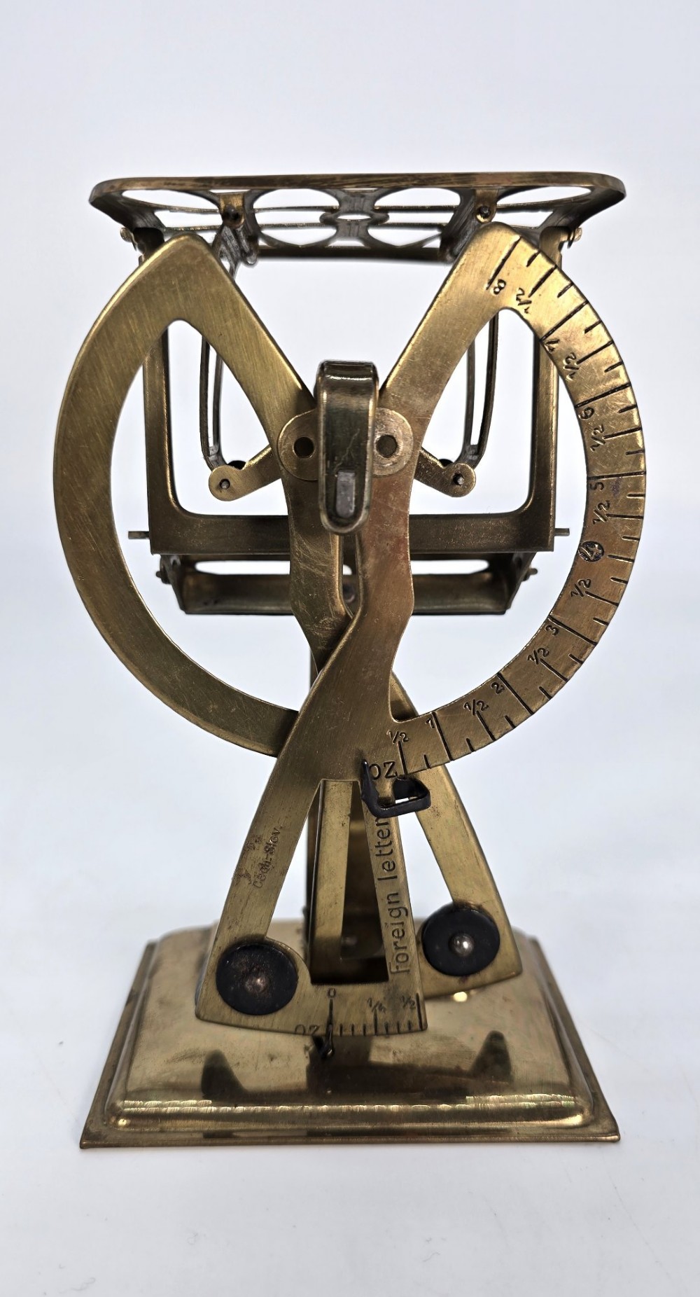 An Edwardian brass postal scale with an engraved curved measurement arc resting on a moulded rectangular base. View II