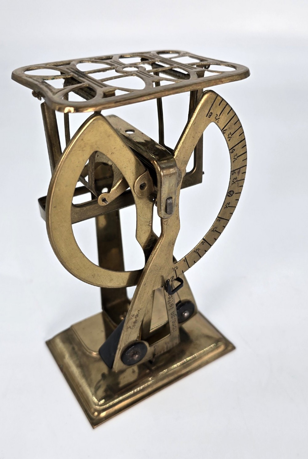 An Edwardian brass postal scale with an engraved curved measurement arc resting on a moulded rectangular base. View III