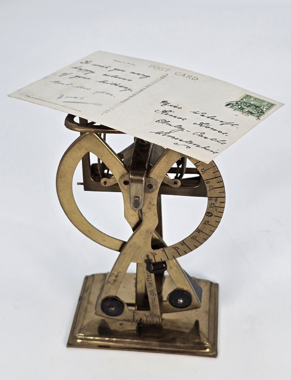 An Edwardian brass postal scale with an engraved curved measurement arc resting on a moulded rectangular base. View IX
