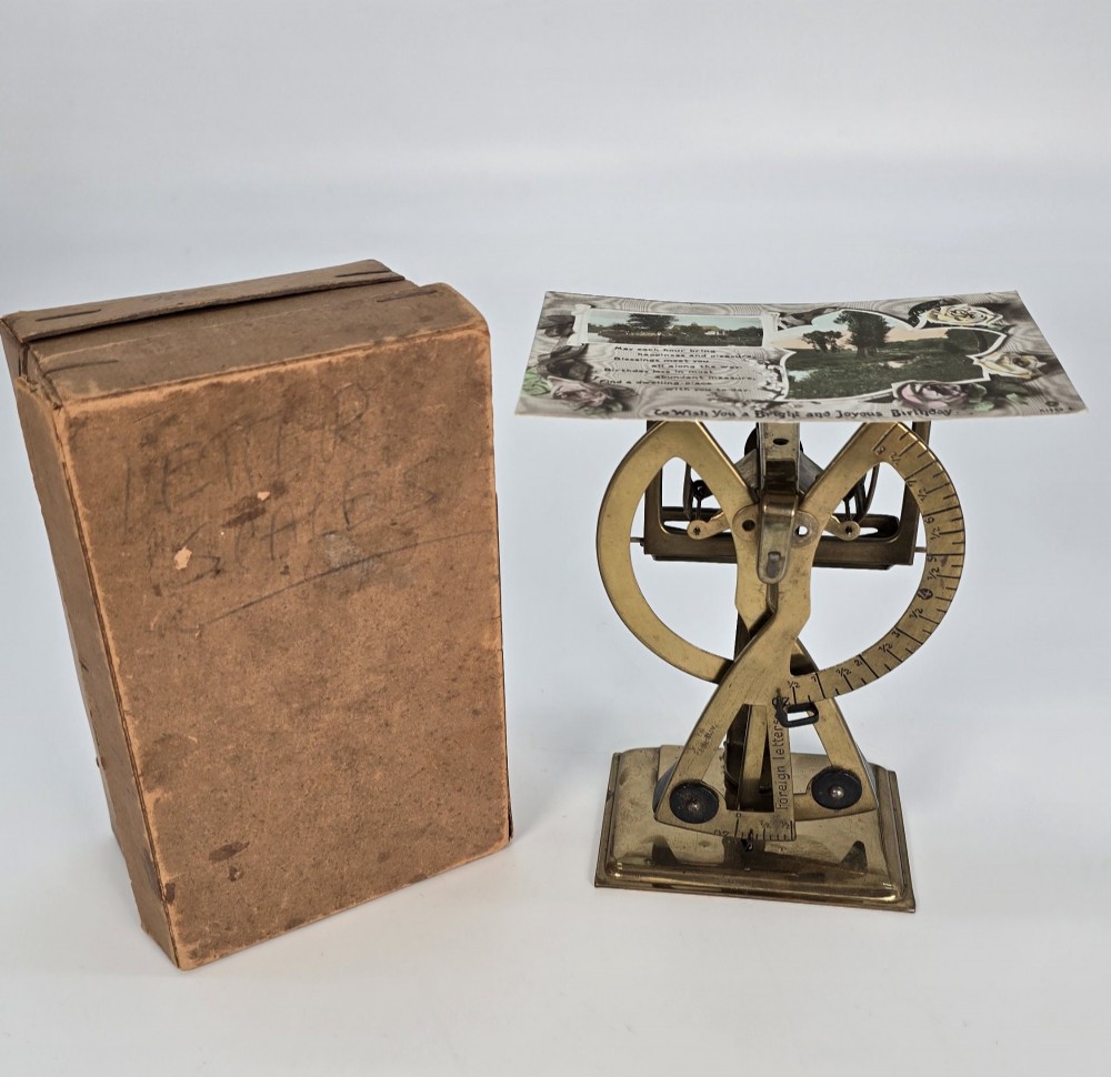 An Edwardian brass postal scale with an engraved curved measurement arc resting on a moulded rectangular base. View XI